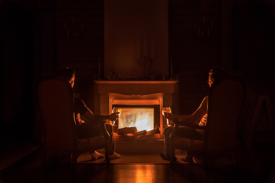 alt="two people sitting in front of a fireplace"